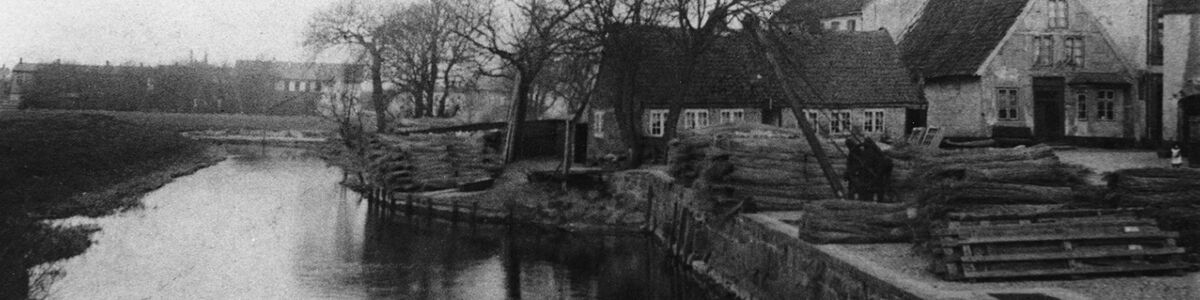 Skibbroen i Tønder med kran og stabler af tagrør. I baggrunden Kogade. Ca.1900
